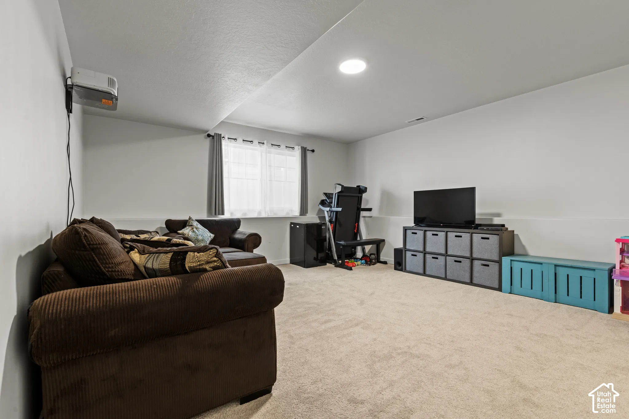 Carpeted flooring, recessed ceiling lighting, and a window with curtains