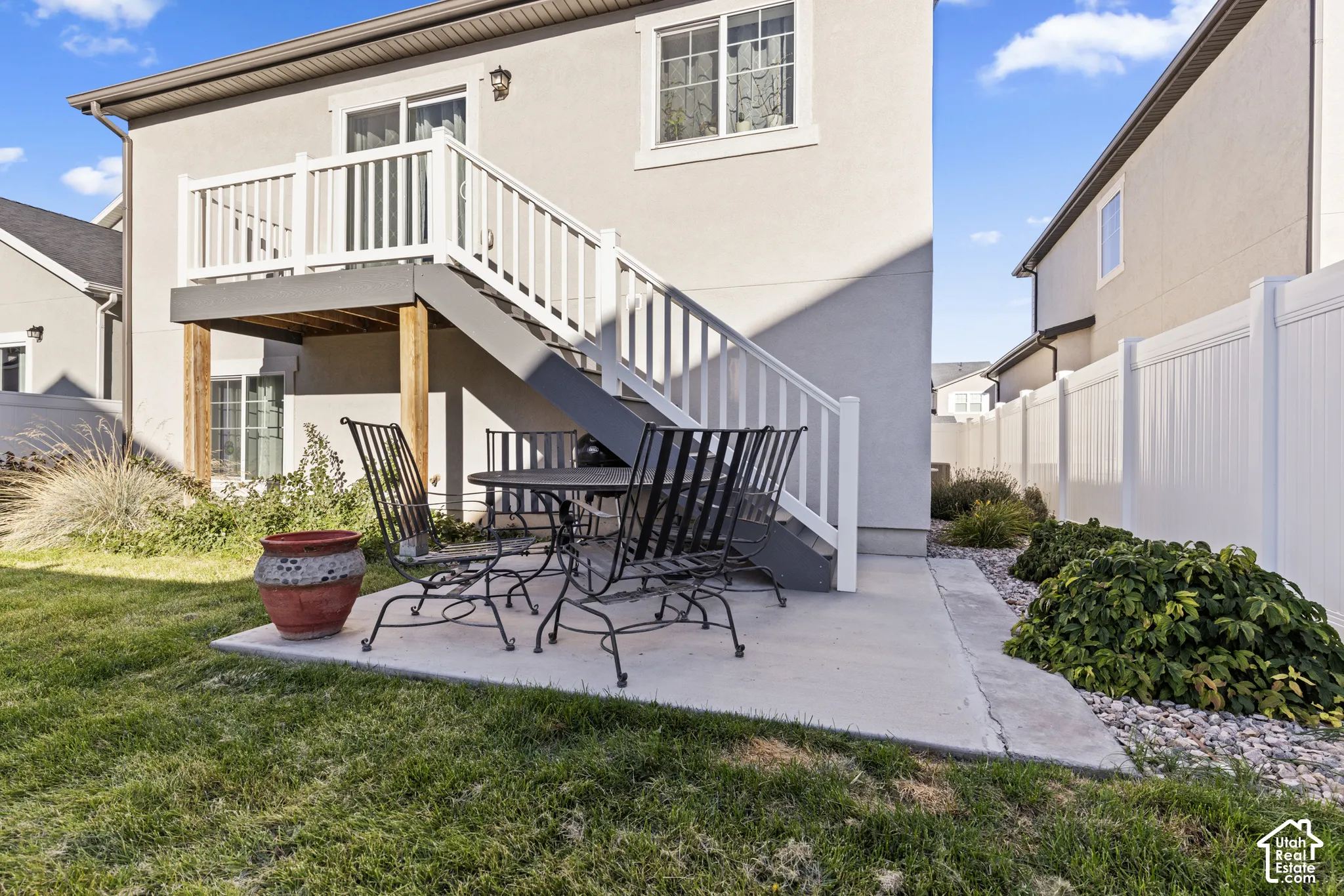 Concrete patio with stair access to an upper-level balcony
