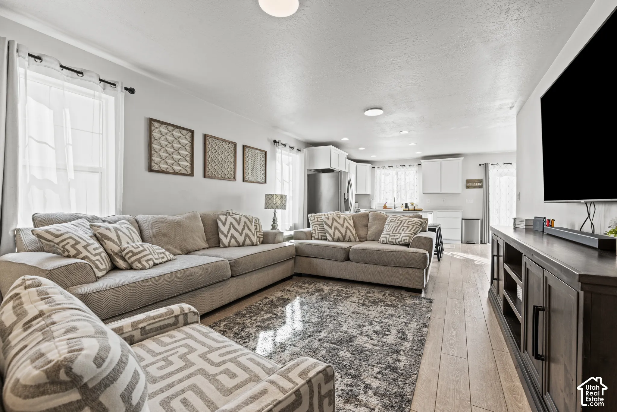 Open-concept living area featuring light wood-finish flooring, recessed lighting, and white walls