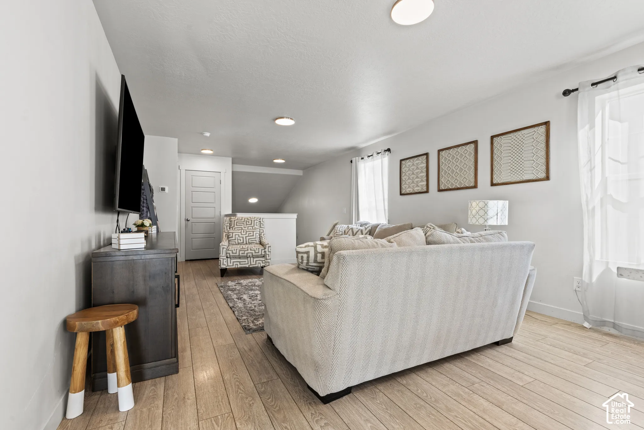 Light wood-finish flooring, recessed lighting, white interior walls, and a five-panel interior door