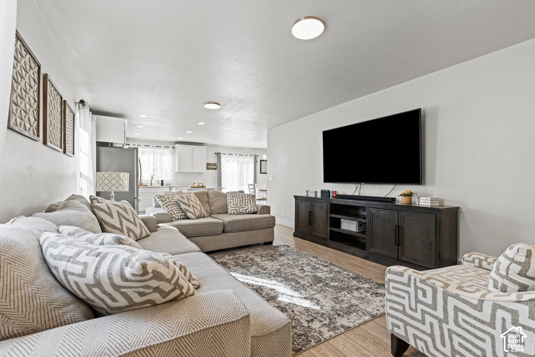 Recessed lighting, wood-finish flooring, white walls, and a built-in media console