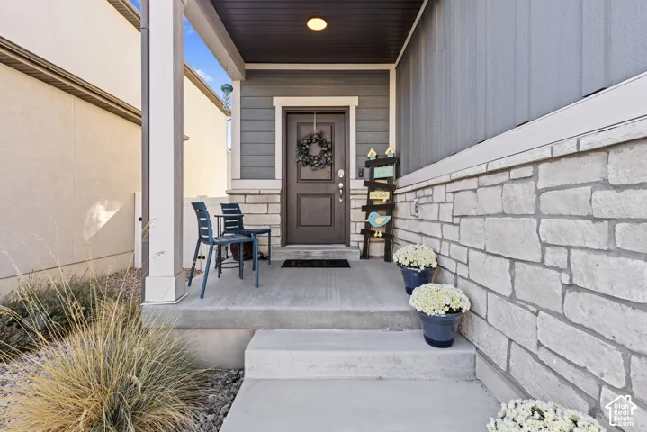 Covered entry with stone veneer accent wall, board and batten siding, and a solid wood entry door