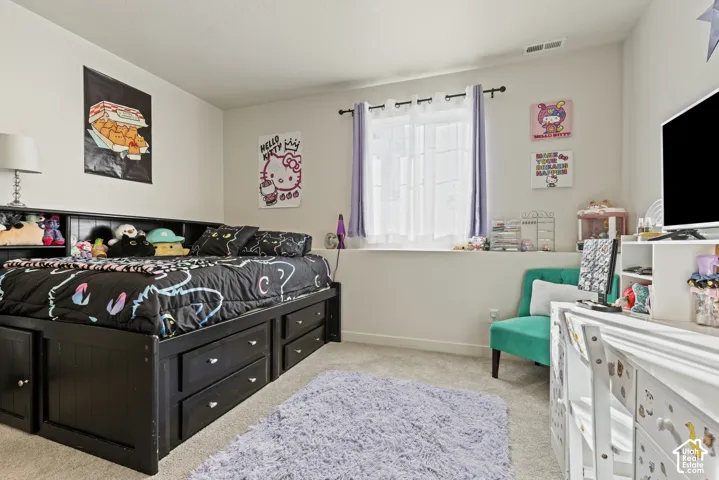 Carpeted flooring, window with curtain rod and sheer curtains, built-in shelving, and light-colored wall paint