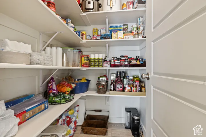 Custom pantry with multiple open shelves and wood-finish flooring