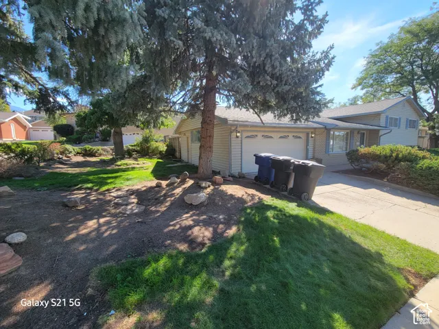 Attached two-car garage, concrete driveway, and mature landscaping