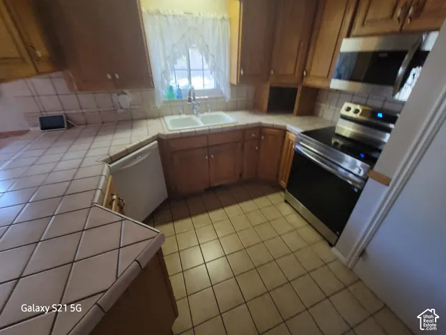 Tile flooring and countertops, wood cabinetry, stainless steel range, and built-in microwave
