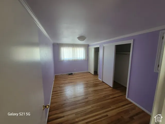 Hardwood flooring, crown molding, double closet, and a ceiling-mounted light fixture