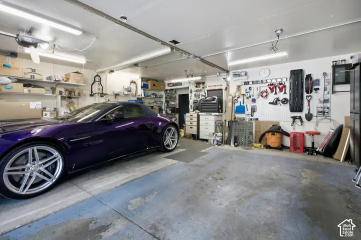 Attached garage space featuring overhead fluorescent lighting and exposed ceiling joists