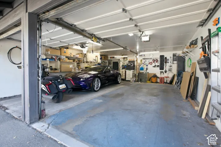 Attached garage with overhead lighting, white garage doors, and concrete flooring