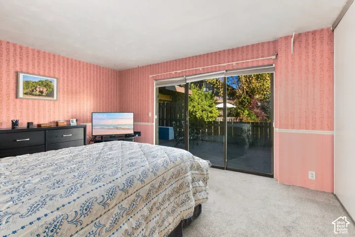 Sliding glass doors opening to an outdoor patio, textured wall paneling, and carpeted flooring