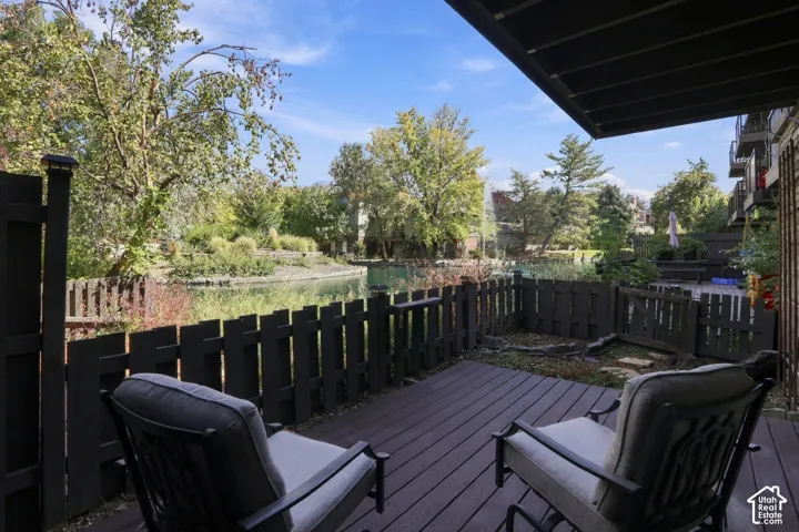 Private deck with wood-finish flooring, dark wood fencing, and water feature