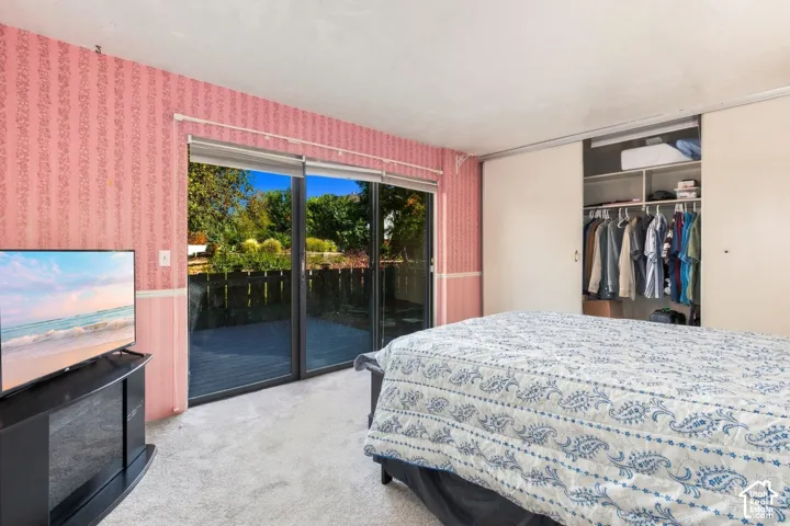 Sliding glass door to exterior, integrated closet storage, and wall-to-wall carpeting