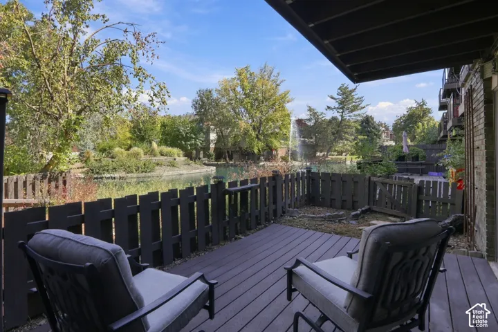 Composite decking with a partial fence enclosure, bordering a water feature with a fountain