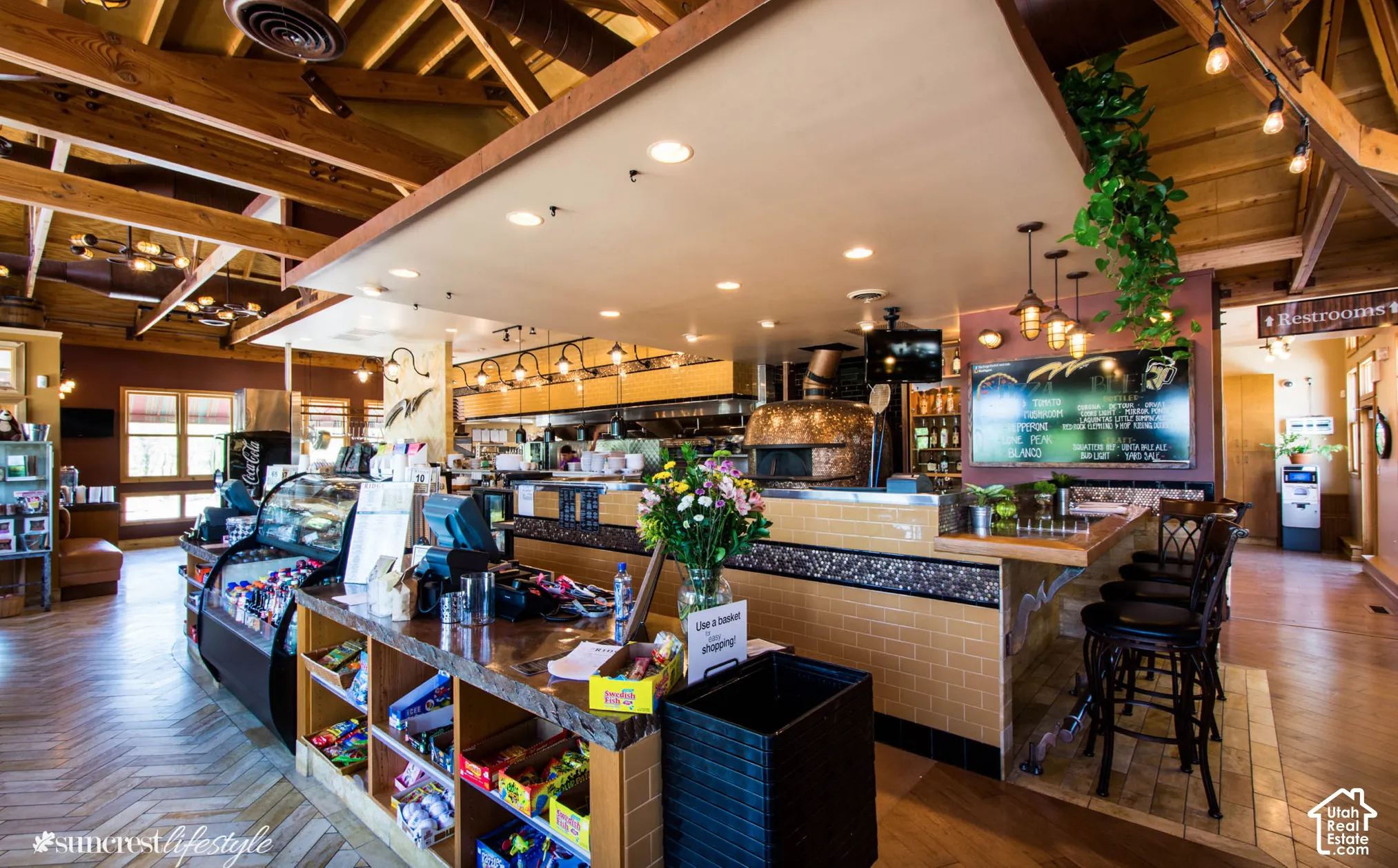 Exposed wood beam ceiling, herringbone-patterned wood-finish flooring, built-in display cases, stone-finish counter, and built-in brick-finish oven