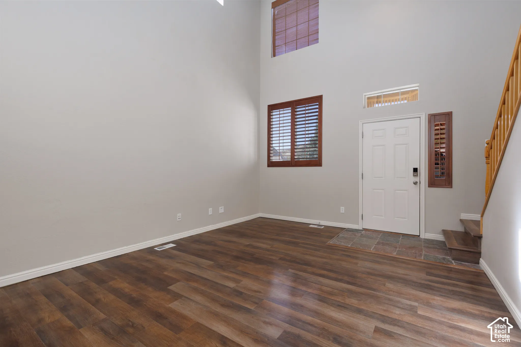 Vaulted ceiling with high transom windows, wood-finish flooring, and a tiled entry