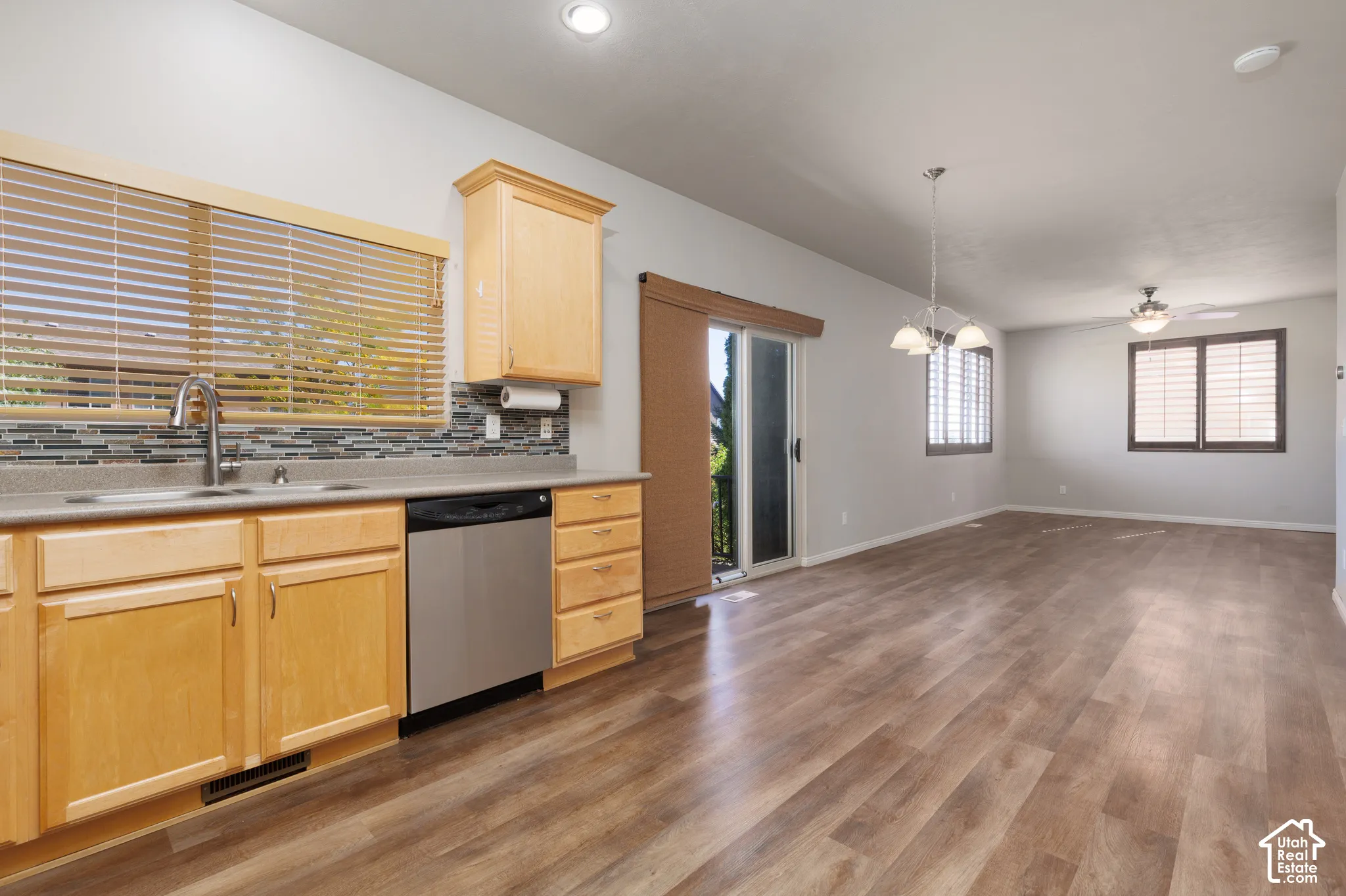 Kitchen area featuring light wood-finish cabinetry, a stainless steel sink with a gooseneck faucet, and a mosaic tile backsplash