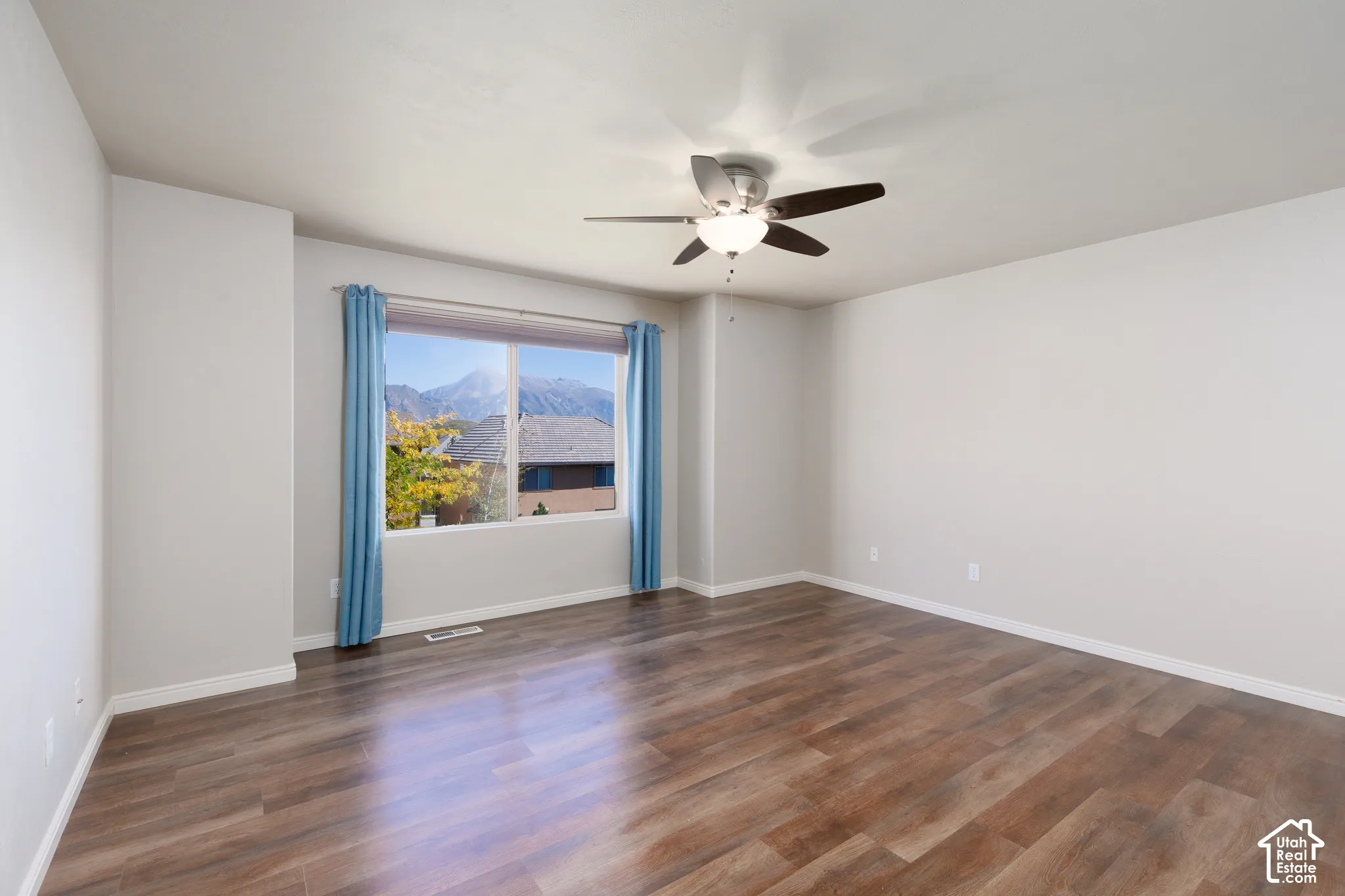 Wood-finish flooring, a large window with a mountain backdrop, and an overhead ceiling fan with lighting