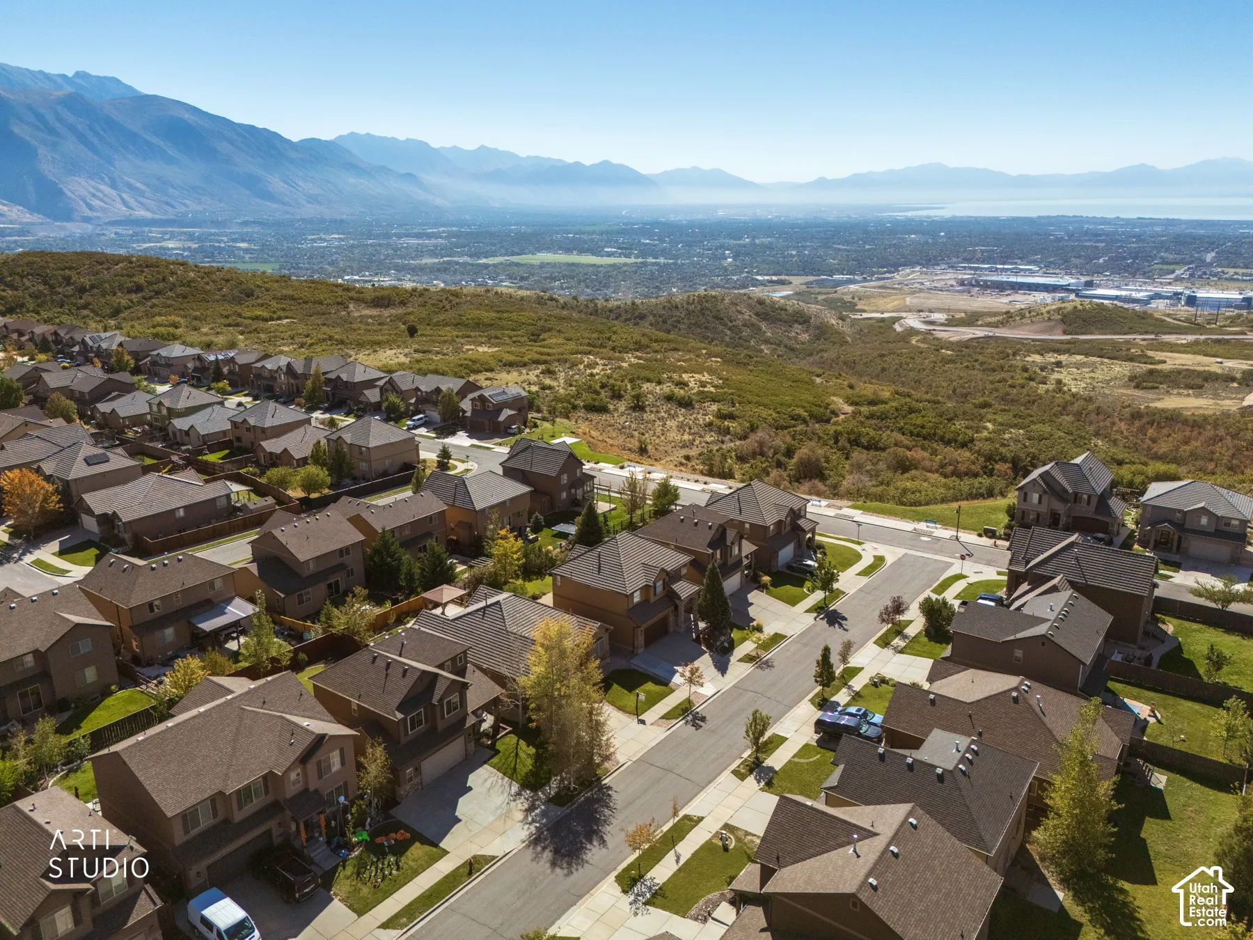 Expansive residential development featuring uniform architecture, mountainous backdrop, and distant body of water