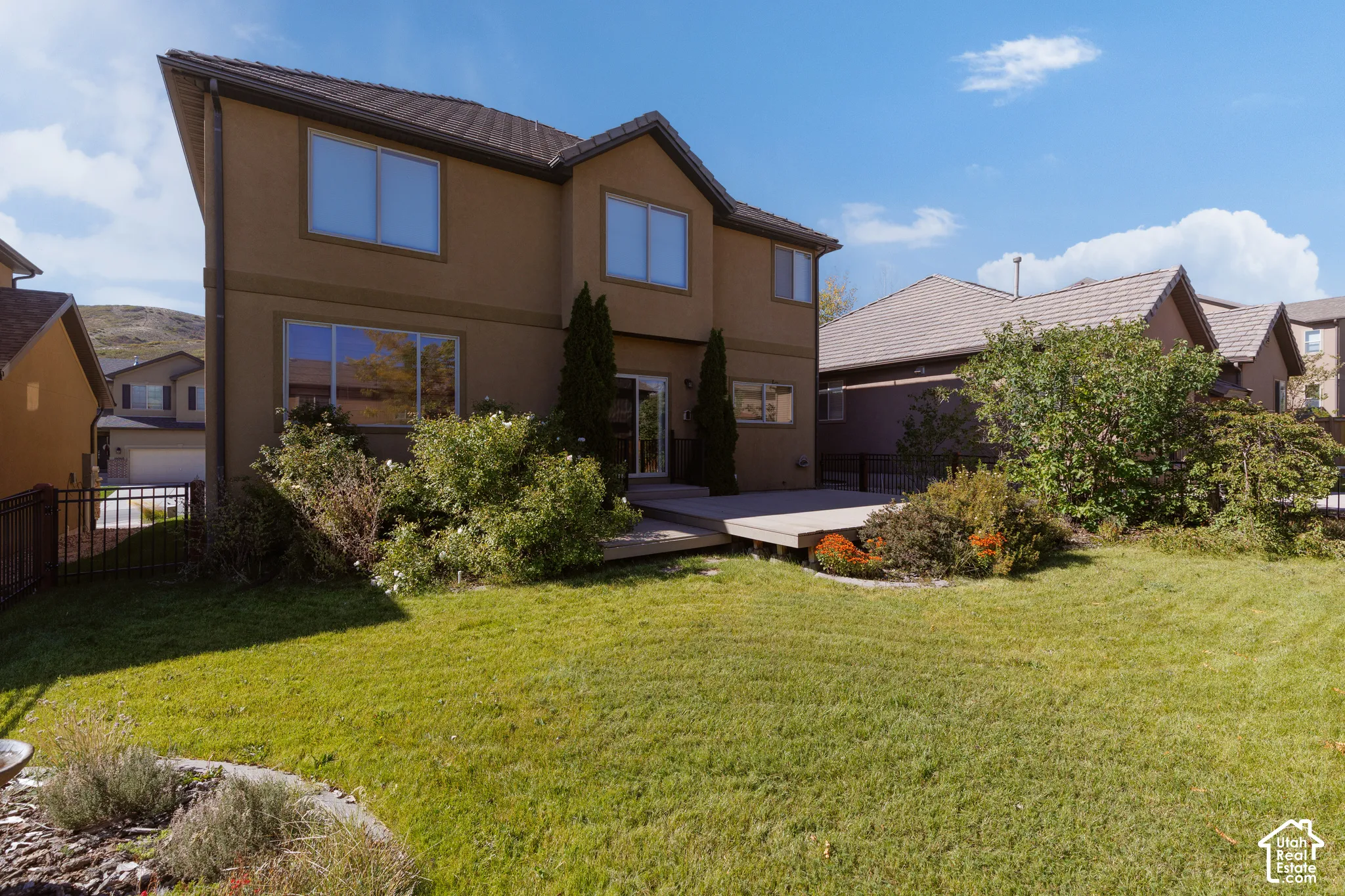 Stucco exterior with multiple windows, leading to a wooden deck