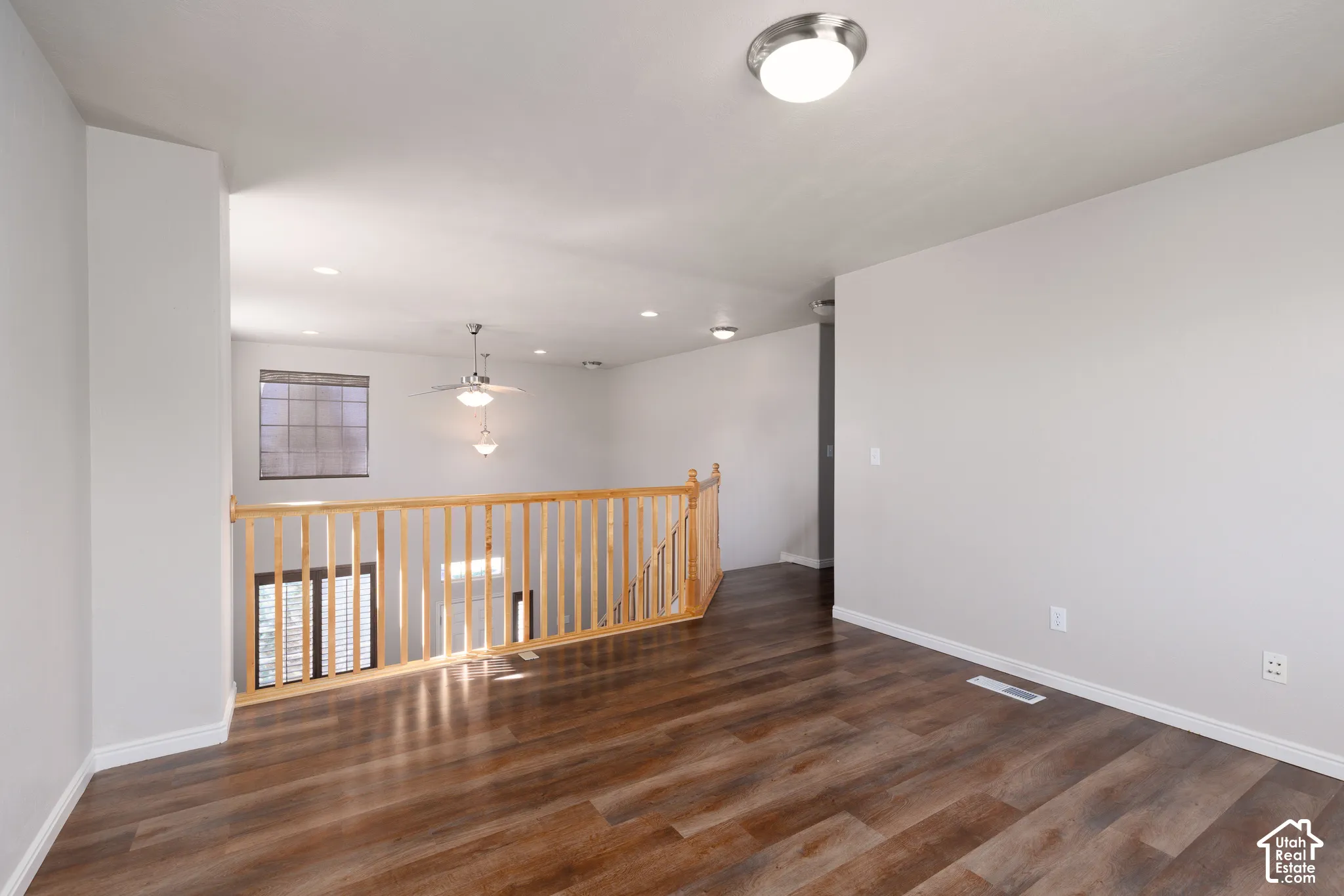 Wood-finish flooring, recessed lighting, and a natural wood staircase railing