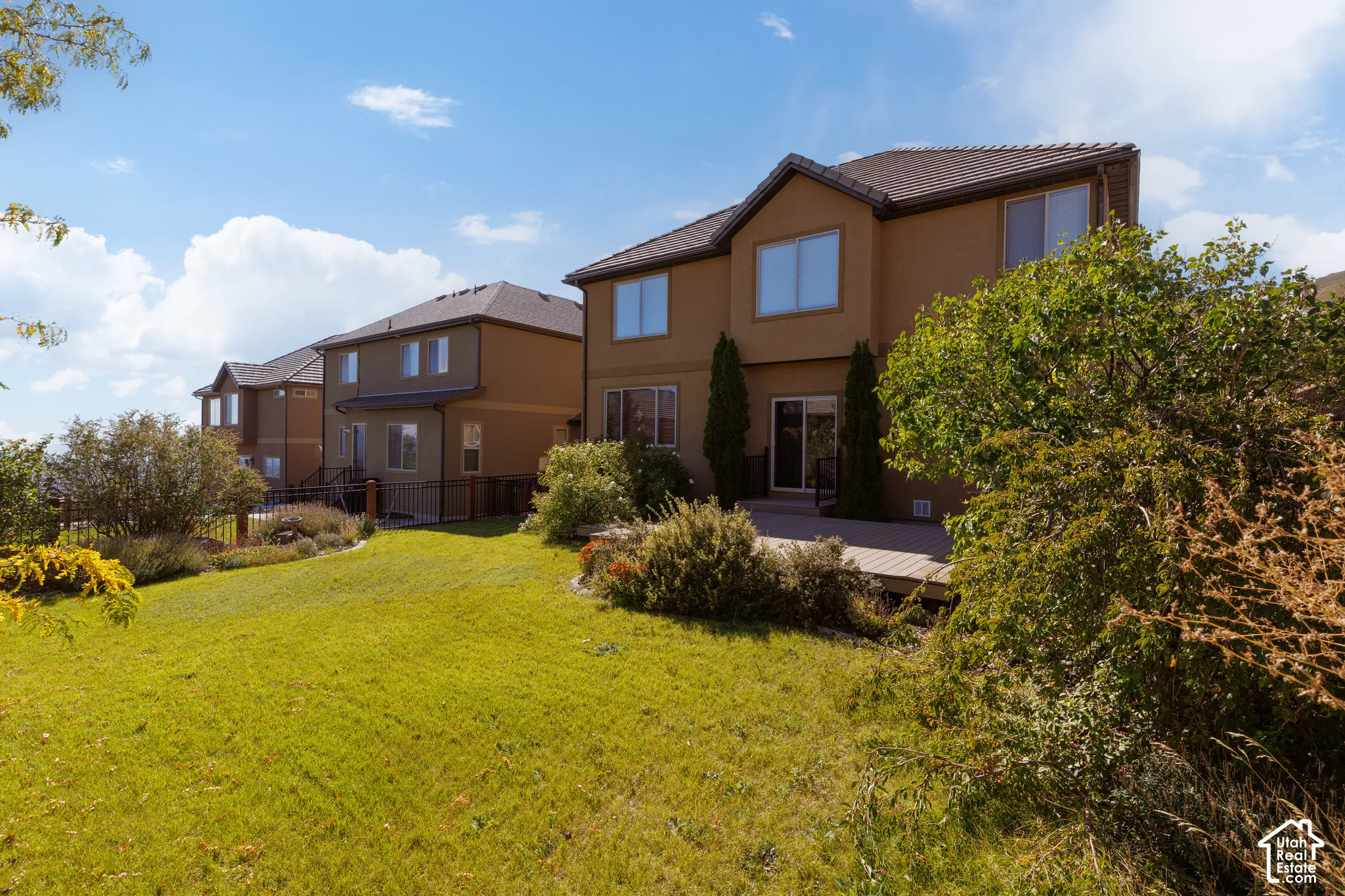 Expansive rear yard with a sloped lawn, mature plantings, and a multi-level wood deck