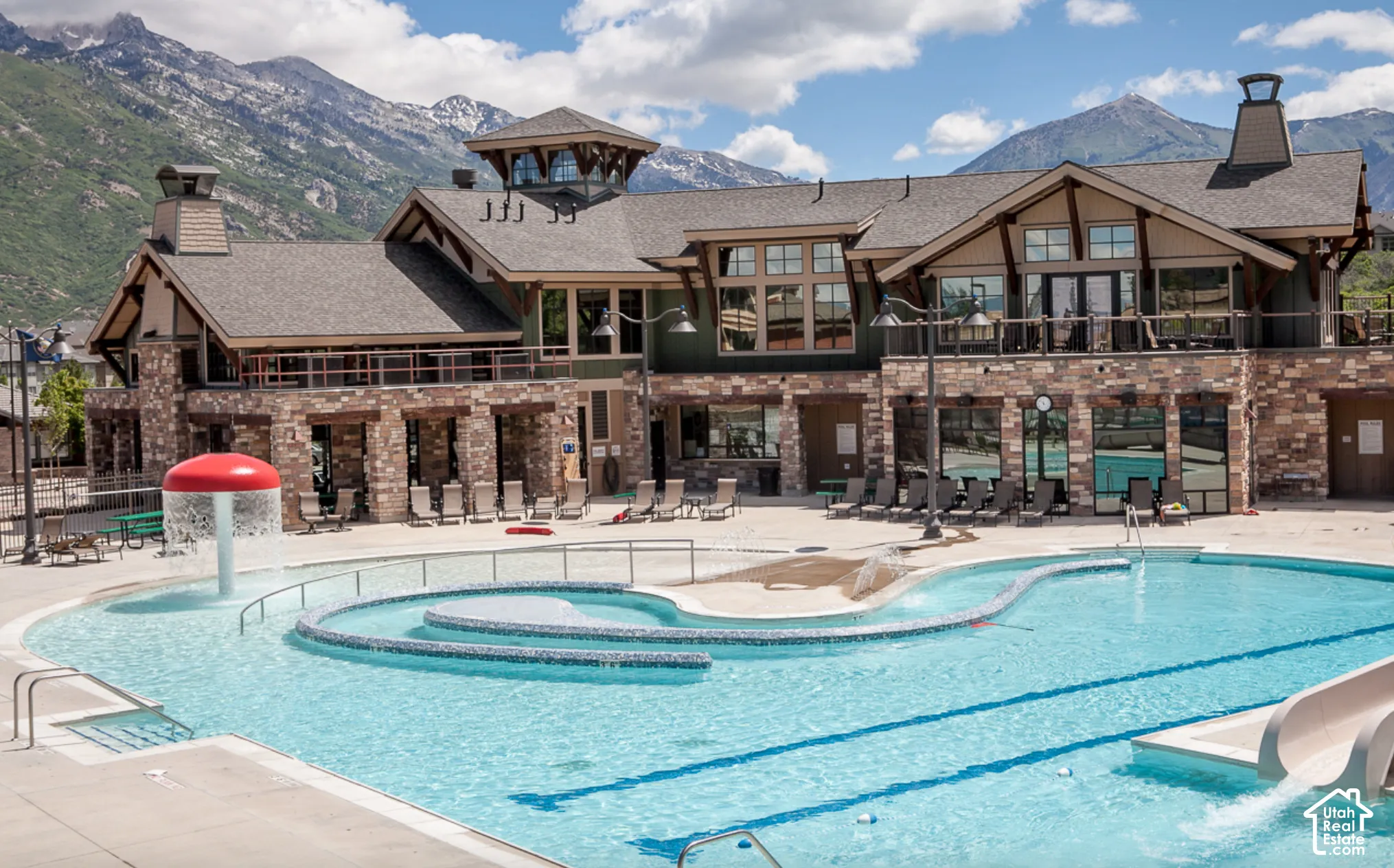 Multi-level outdoor pool with integrated water slide and sun shelf, featuring a dedicated splash pad with water features