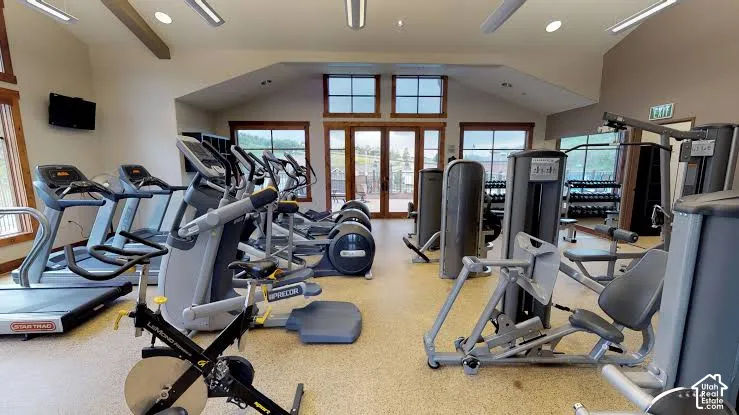 Fitness center featuring varied exercise equipment, wood-trim windows, and an exterior patio access