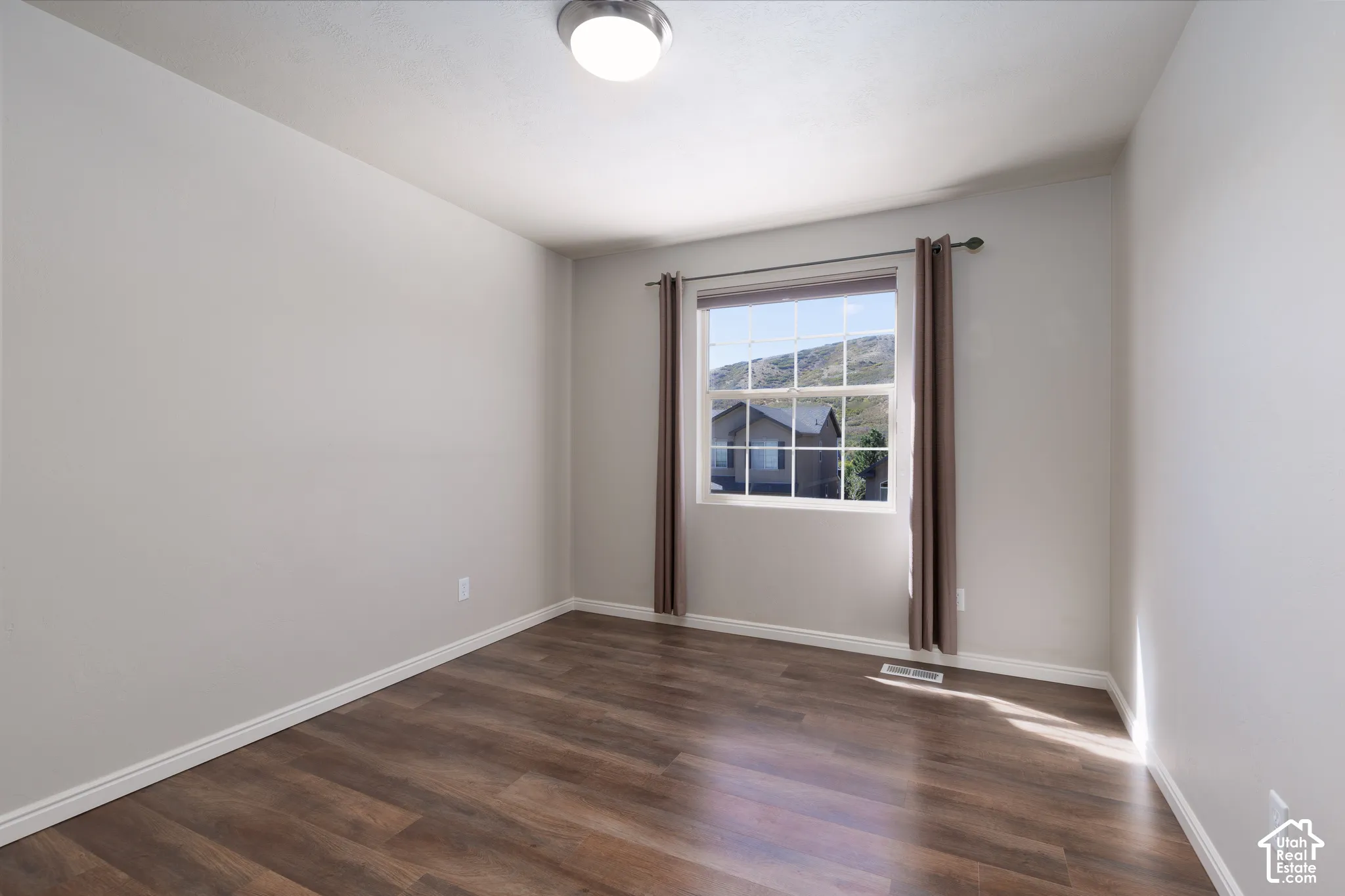 Wood-finish flooring, single window, flush-mount ceiling light fixture, white walls, and white trim