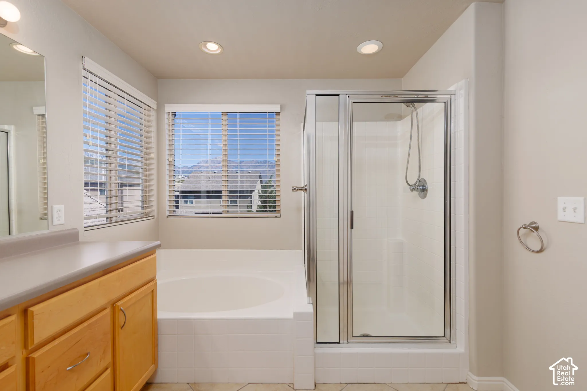 Recessed lighting, wood-finish cabinetry, built-in bathtub, glass-enclosed shower, and tile flooring