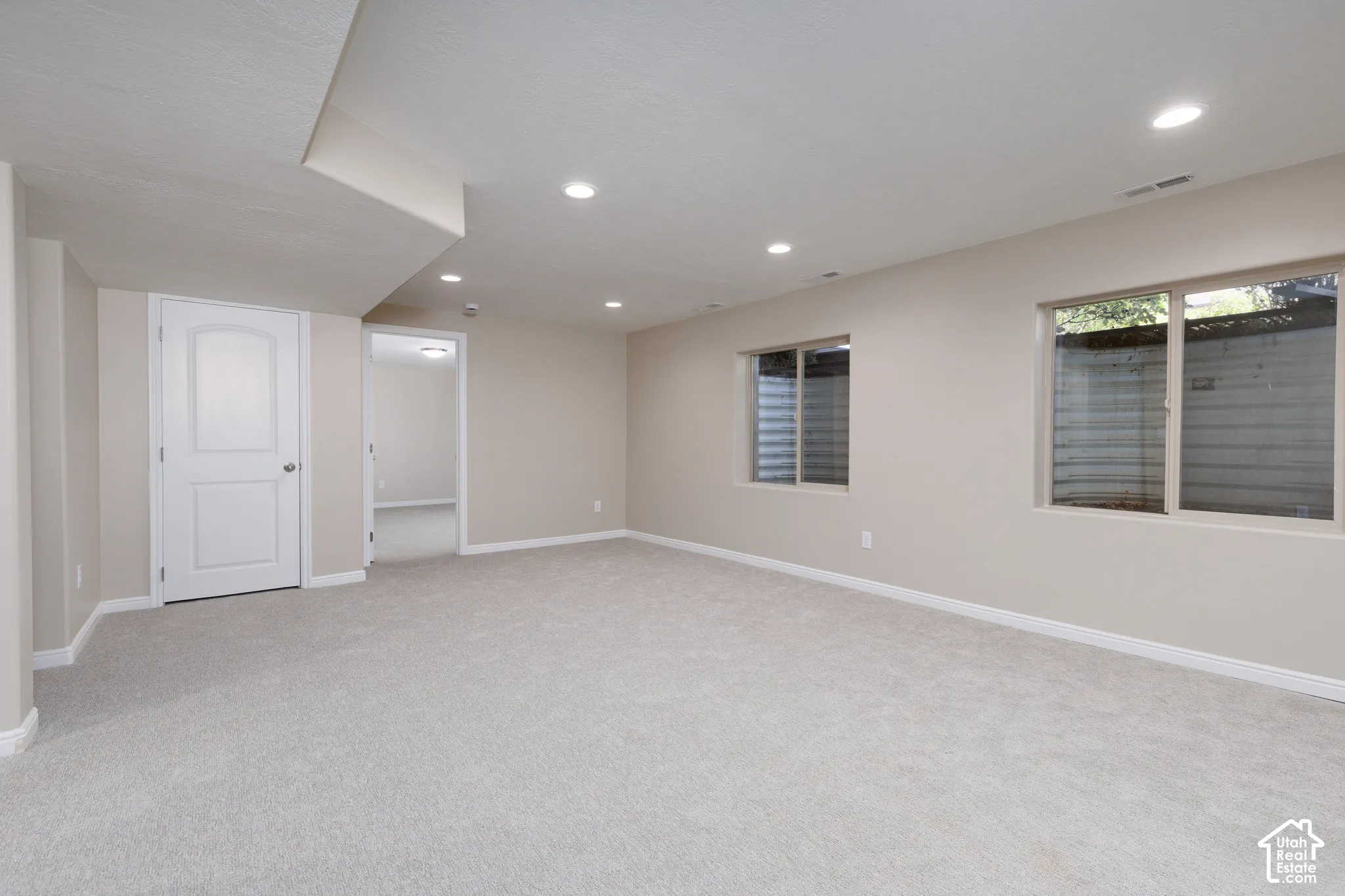 Expansive room featuring recessed lighting, light-toned carpeting, two windows, and neutral wall paint