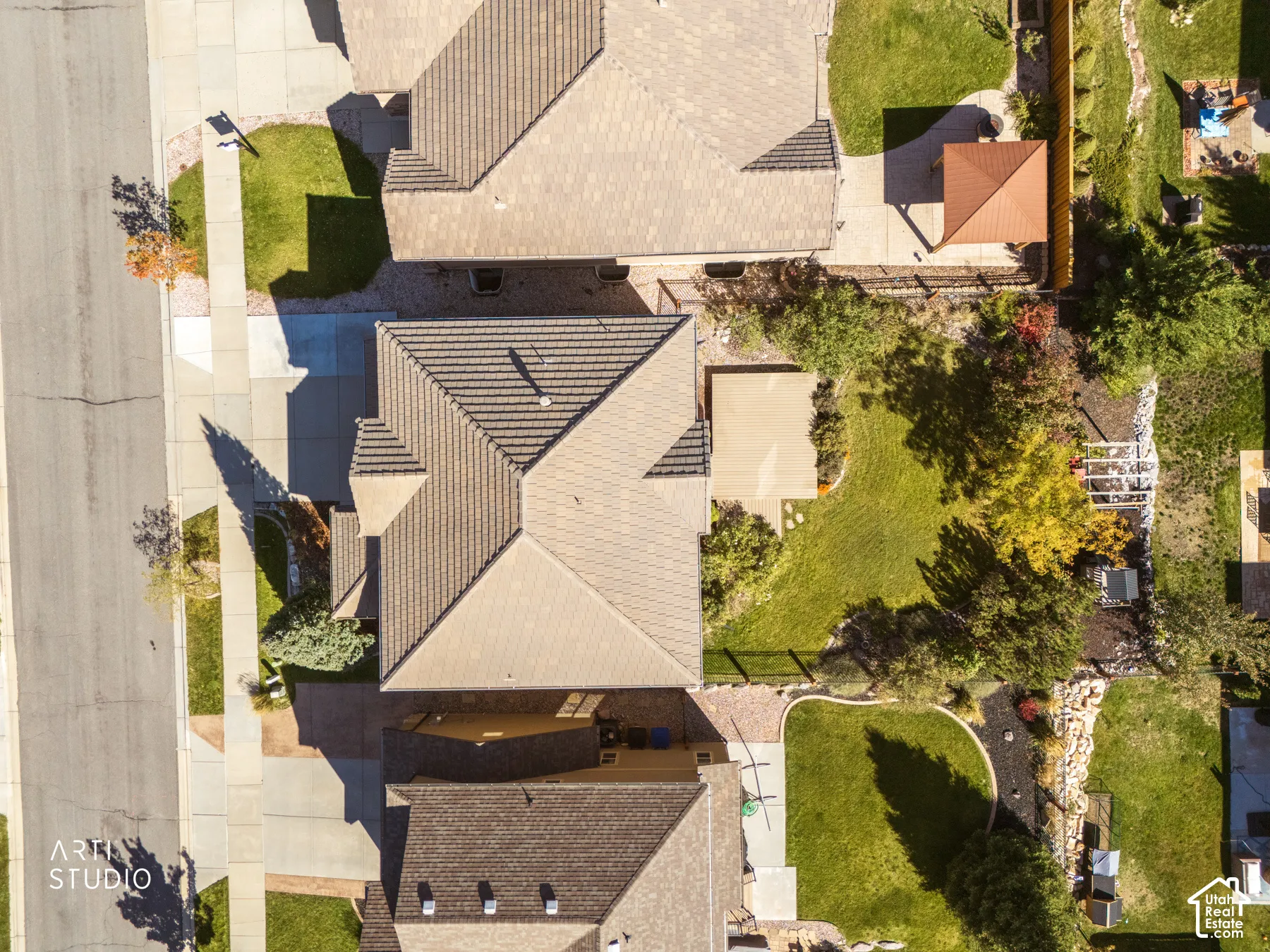 Aerial view showcasing a well-designed residential property with multiple roof lines featuring dimensional shingles, manicured lawn areas with mature landscaping, and defined hardscaped pathways