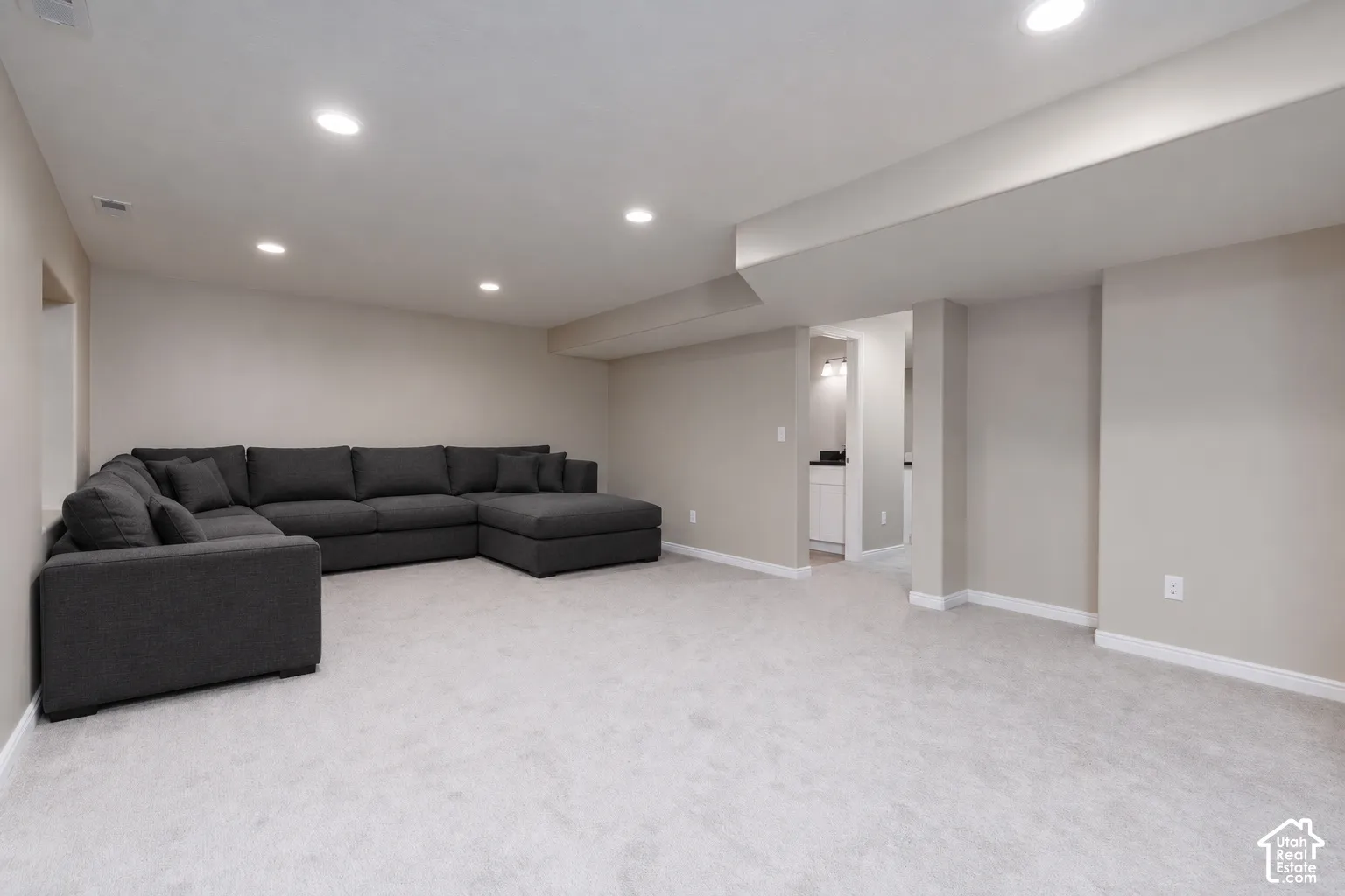 Recessed lighting, light gray carpet, neutral wall tones, and white trim accents