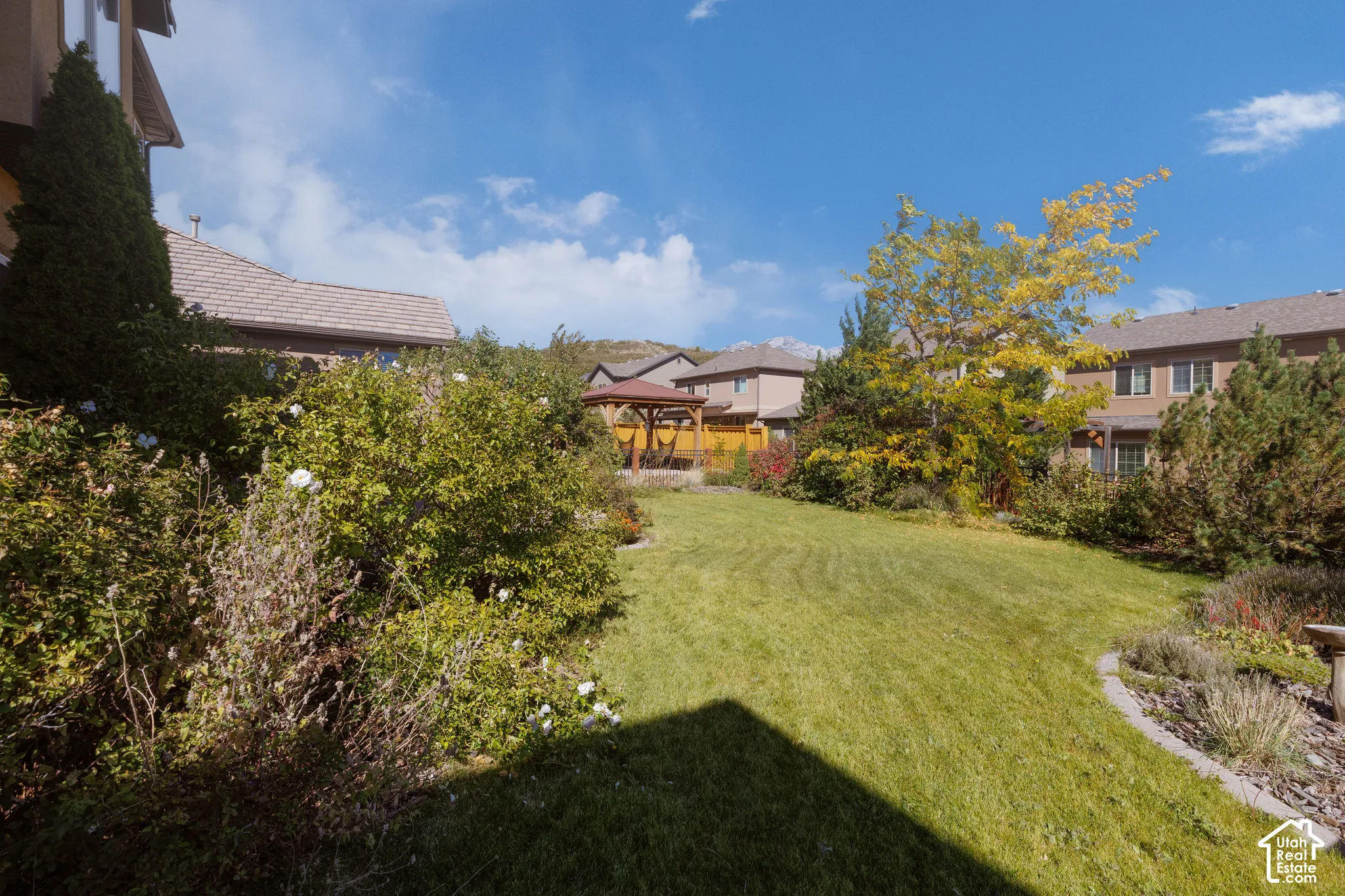 Expansive lawn area, established landscaping, and a built-in gazebo