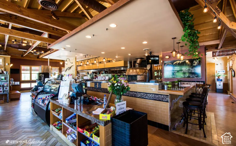 Exposed wood beam ceiling, herringbone-patterned wood-finish flooring, built-in display cases, stone-finish counter, and built-in brick-finish oven