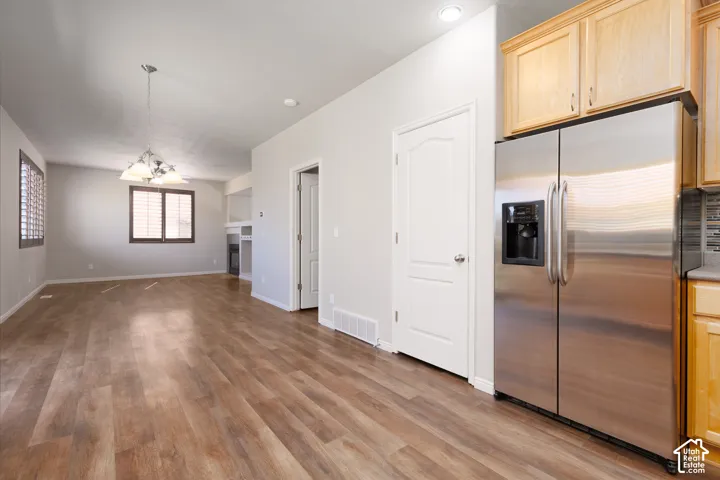 Wood-finish flooring throughout, recessed lighting, and a stainless steel side-by-side refrigerator