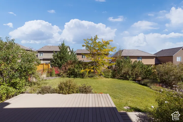 Expansive backyard featuring a manicured lawn, established landscaping, and a composite deck