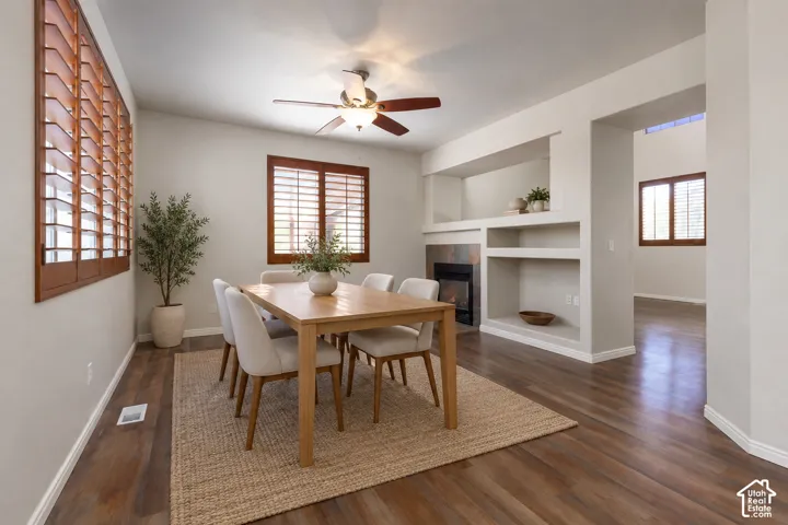 Wood-finish flooring throughout, solid wood plantation shutters, built-in shelving, stone-surround fireplace, and ceiling fan with integrated lighting