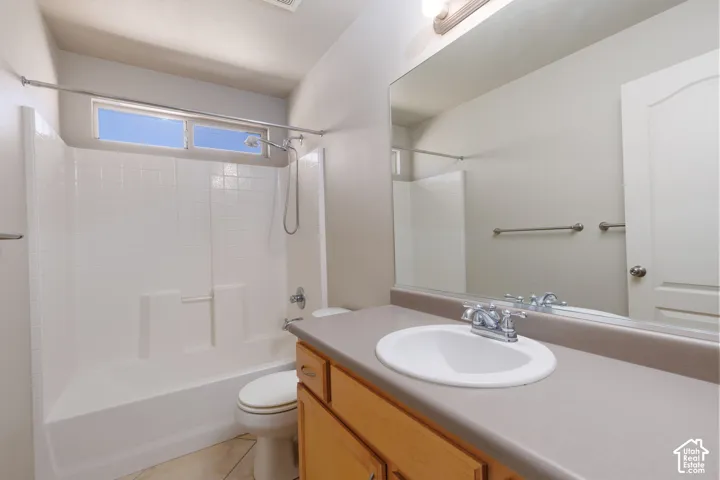 Full bath featuring a tub/shower combination with white tile surround, wood-finish vanity with an integrated sink, and an expansive wall-mounted mirror