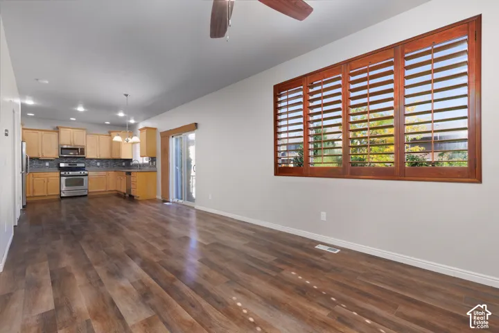 Open-concept living space featuring wood-finish flooring, a kitchen with stainless steel appliances, and a sliding glass door