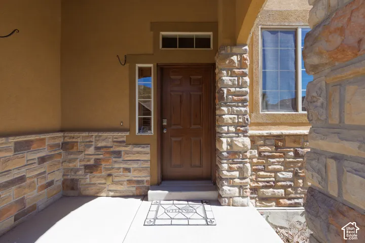 Entryway featuring a paneled wood door, stone veneer accents, stucco exterior, and transom window