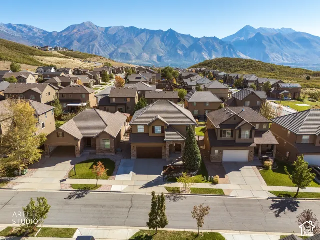 Mountain-backed neighborhood setting featuring multiple residential properties with pitched roofs, varied exterior finishes, and attached garages