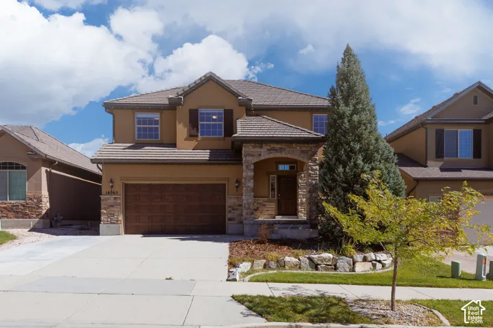 Stucco exterior with stone accents, a covered entry, an attached garage, and a concrete driveway