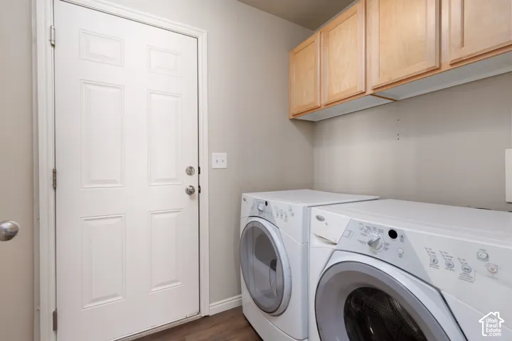 Laundry area featuring wood-finish flooring, overhead cabinetry, and light-toned walls