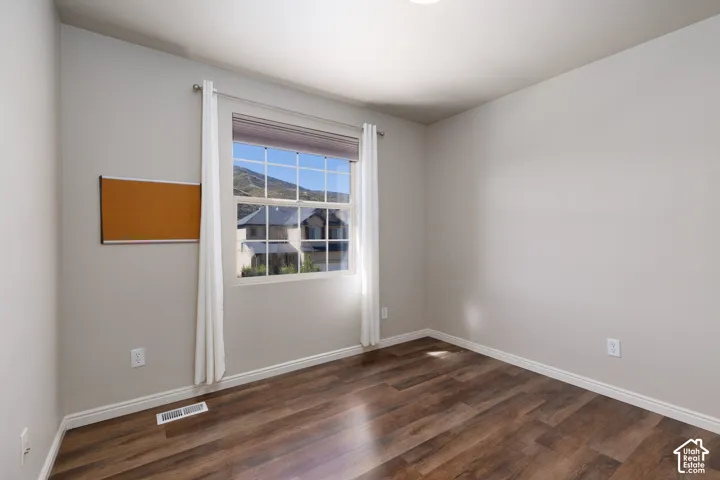 Wood-finish flooring, white trim, and a window with muntins