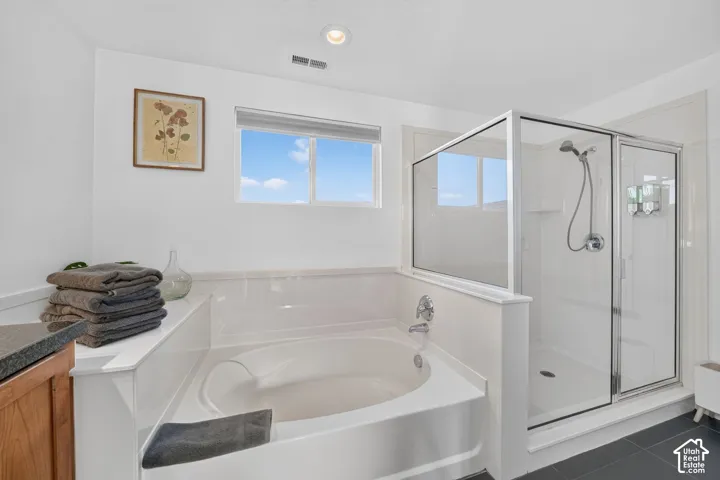 Built-in soaking tub with chrome fixtures, enclosed glass shower, and a large window