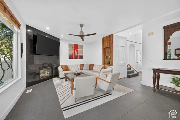 Living area featuring a modern linear fireplace with black tile surround, a built-in wood-finish shelving unit, recessed lighting, and a ceiling fan