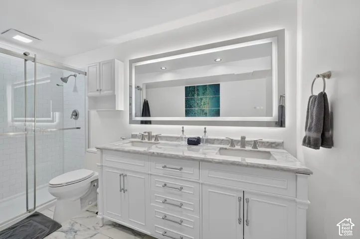 White double vanity with a marble countertop, dual undermount sinks, and an illuminated mirror