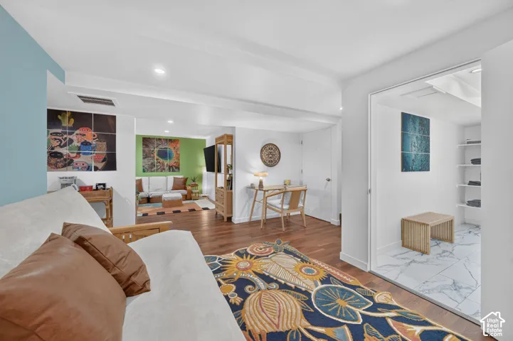 Wood-finish flooring throughout, white walls, recessed lighting, and a separate space with white shelving and tile flooring