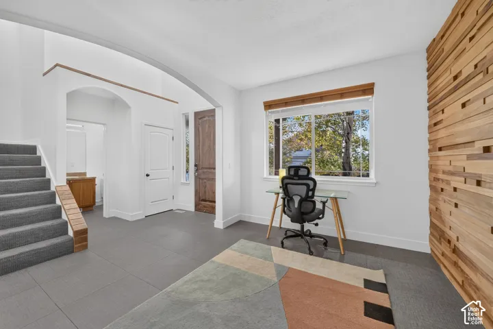 Expansive entry with tiled flooring, arched doorway, and a wood-paneled accent wall
