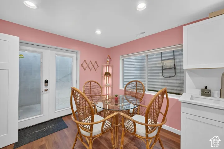 Recessed ceiling lighting, wood-finish flooring, white French doors, a large egress window, and white cabinetry